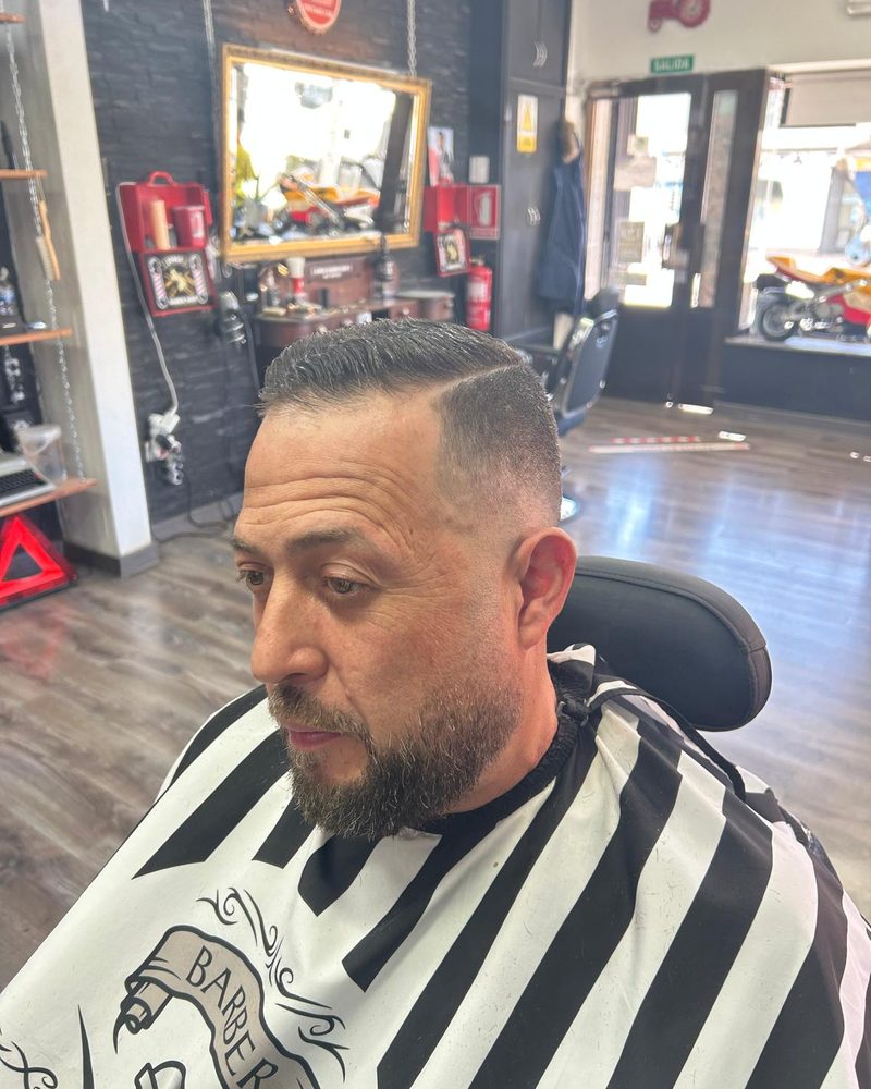 Corte con degradado y la barba arreglada.